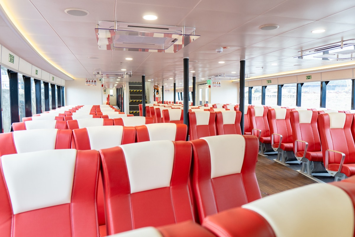 Economy Class cabin with red and olive seating and wide windows